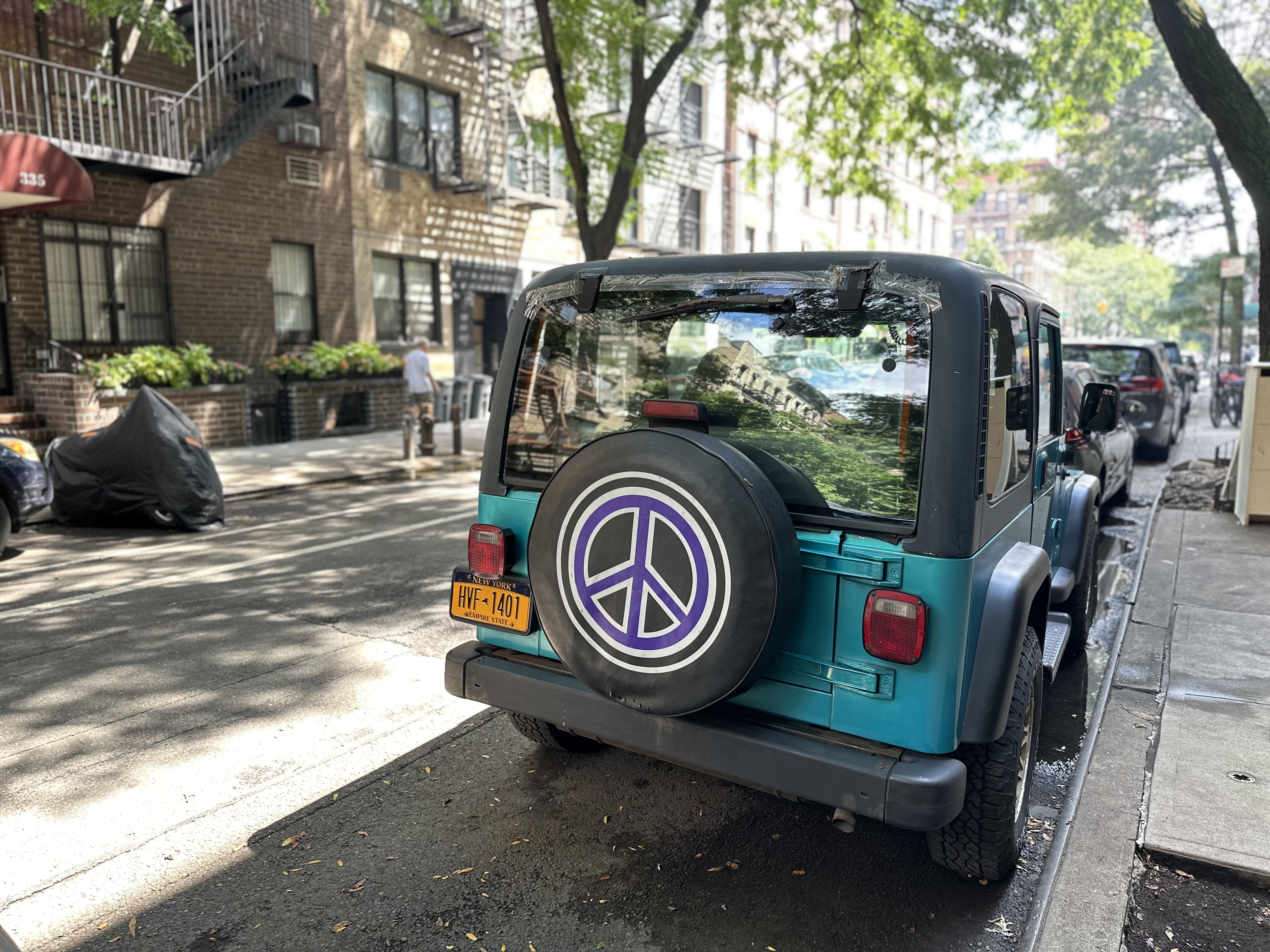 This car's tire cover on E90th Street carries a peace symbol. 